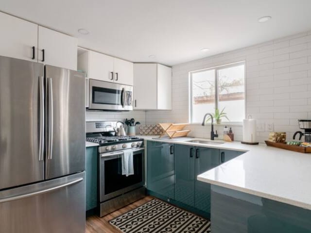 kitchen featuring white cabinets, sink, light hardwood / wood-style flooring, decorative backsplash, and stainless steel appliances