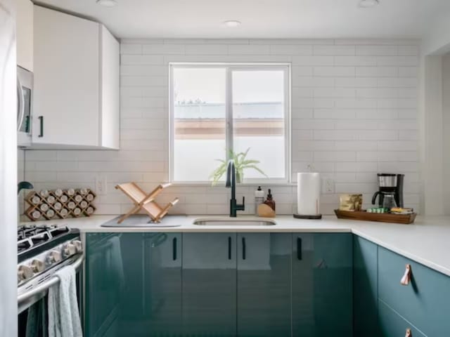 kitchen with appliances with stainless steel finishes, tasteful backsplash, white cabinetry, and sink