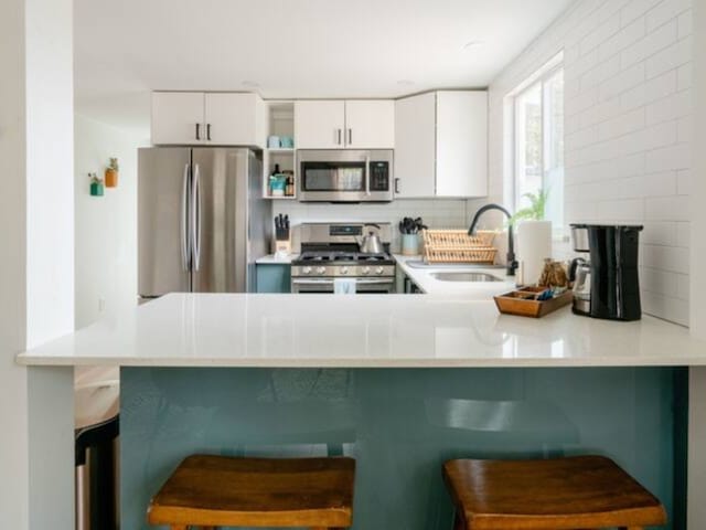 kitchen featuring kitchen peninsula, appliances with stainless steel finishes, a breakfast bar area, and sink