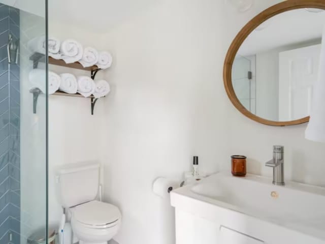 bathroom featuring tiled shower, vanity, and toilet