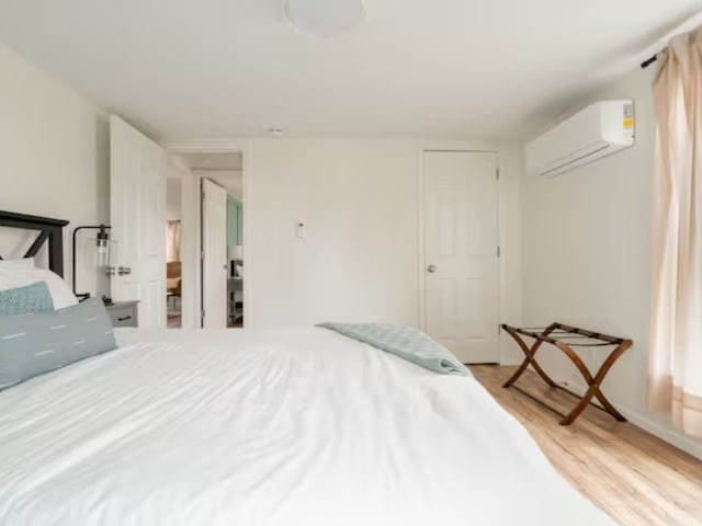 bedroom featuring a wall unit AC and light wood-type flooring