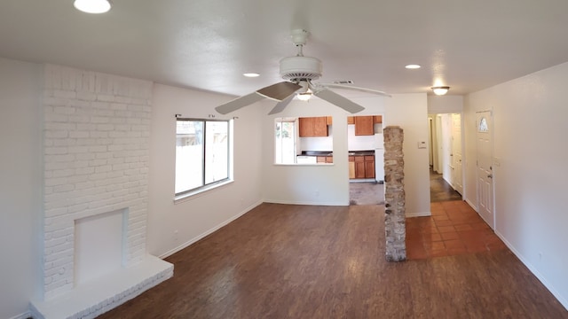 unfurnished living room featuring a fireplace, dark hardwood / wood-style flooring, and ceiling fan