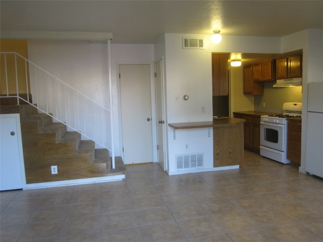 kitchen featuring kitchen peninsula, white appliances, and light tile patterned flooring