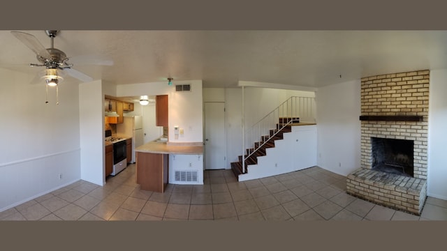 kitchen with ceiling fan, light tile patterned floors, white appliances, and a brick fireplace