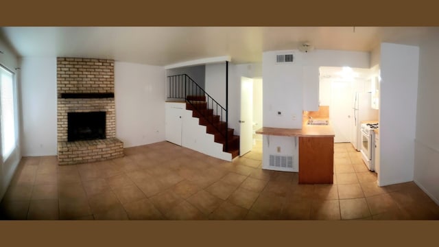 unfurnished living room with sink, light tile patterned floors, and a brick fireplace