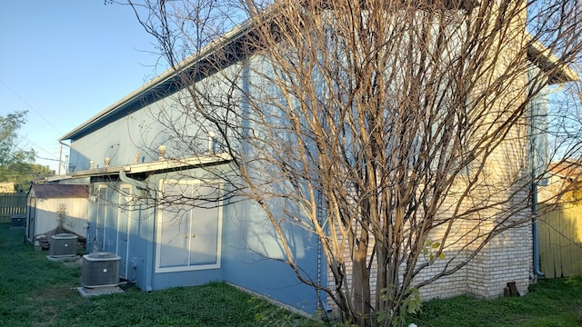 view of side of property with a yard and cooling unit