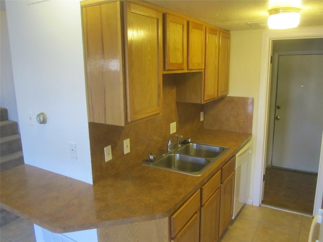 kitchen with decorative backsplash, kitchen peninsula, sink, dishwasher, and light tile patterned flooring