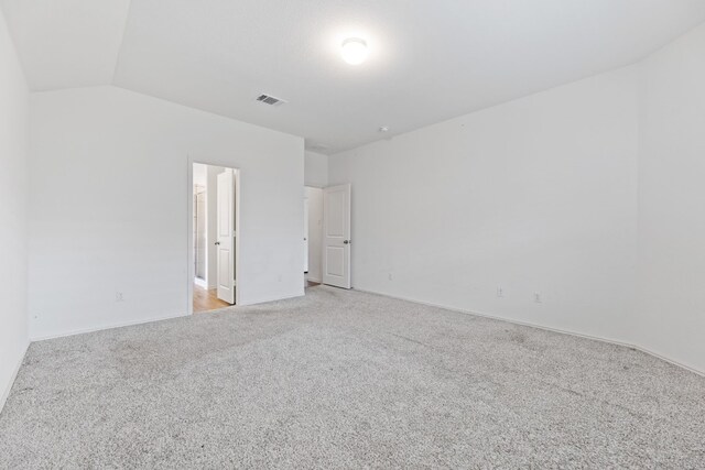 empty room featuring light colored carpet and lofted ceiling