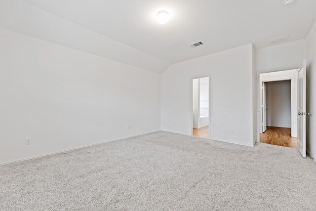 carpeted empty room with vaulted ceiling