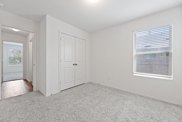 unfurnished bedroom featuring light carpet and a closet