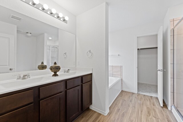 bathroom with hardwood / wood-style floors, vanity, and independent shower and bath