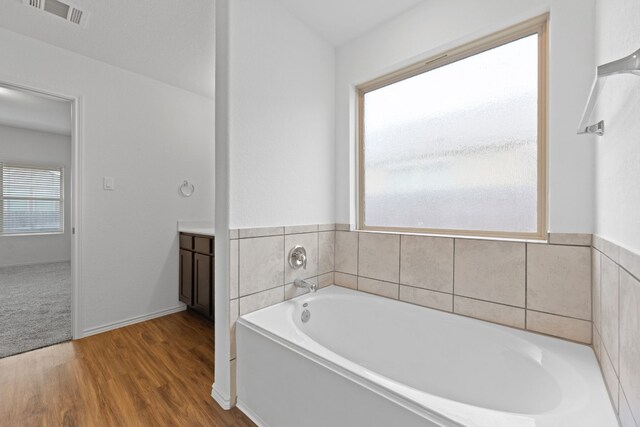 bathroom with wood-type flooring, vanity, and a bathtub