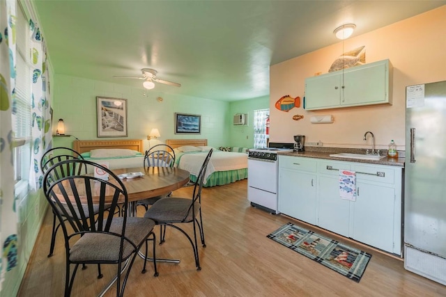 kitchen featuring white range, sink, ceiling fan, light wood-type flooring, and stainless steel refrigerator