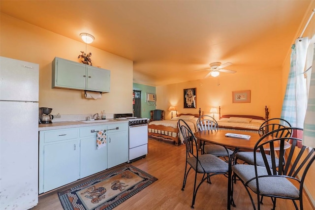 kitchen featuring ceiling fan, sink, light hardwood / wood-style floors, and white appliances