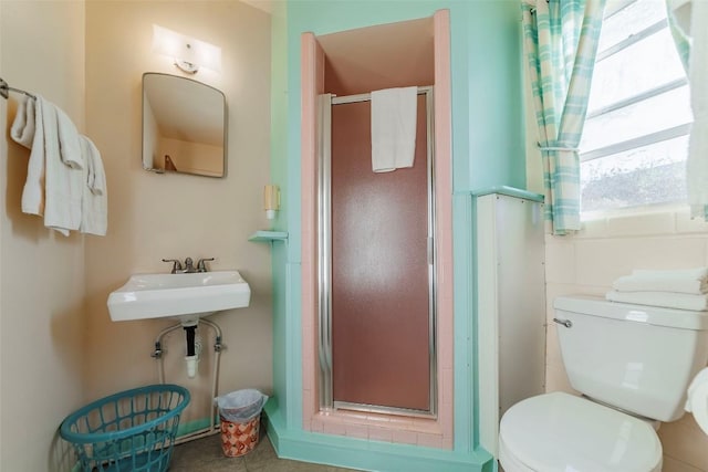 bathroom featuring sink, a shower with shower door, and toilet