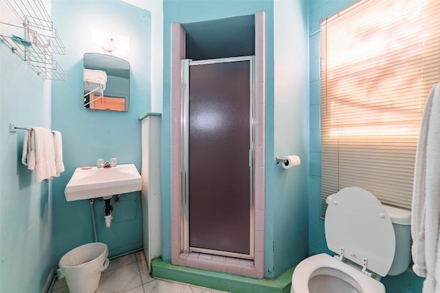 bathroom with toilet, a shower with door, and sink