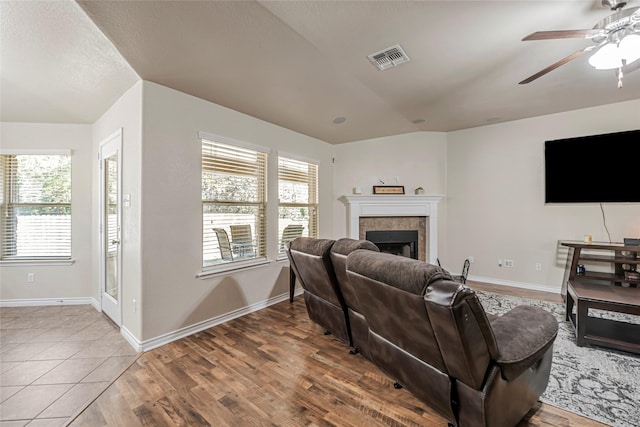 living room featuring tile patterned flooring, a tile fireplace, ceiling fan, and lofted ceiling