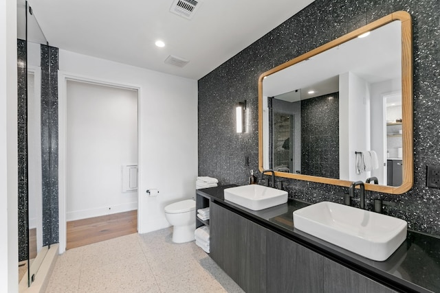 bathroom with vanity, toilet, walk in shower, and tile walls