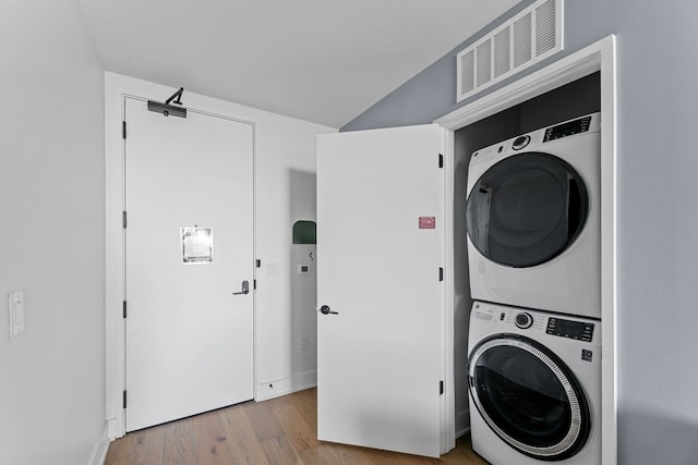 laundry area with light wood-type flooring and stacked washer / dryer