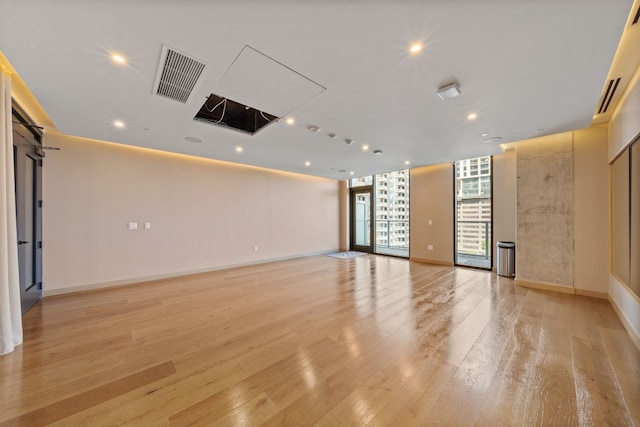 spare room featuring floor to ceiling windows and light hardwood / wood-style floors