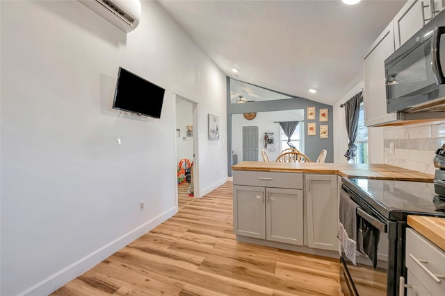 kitchen with white cabinetry, a wall mounted air conditioner, light hardwood / wood-style flooring, butcher block countertops, and black appliances