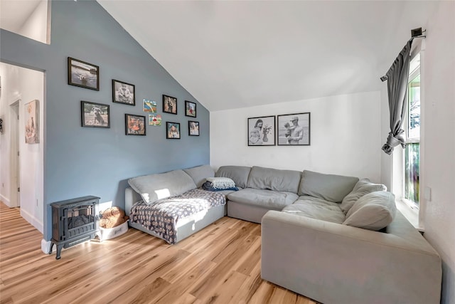 living room featuring lofted ceiling, a wood stove, and light hardwood / wood-style flooring