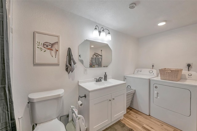 bathroom with vanity, hardwood / wood-style flooring, toilet, and washer and clothes dryer