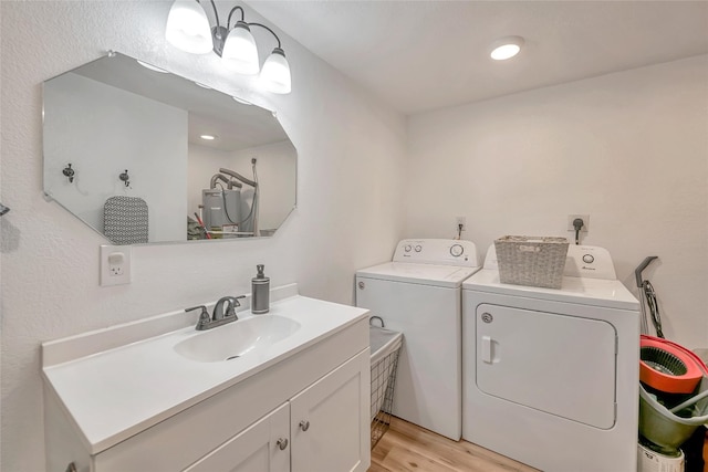 washroom featuring light wood-type flooring, washer and clothes dryer, and sink