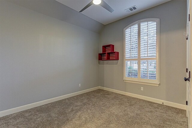 carpeted spare room featuring vaulted ceiling and ceiling fan