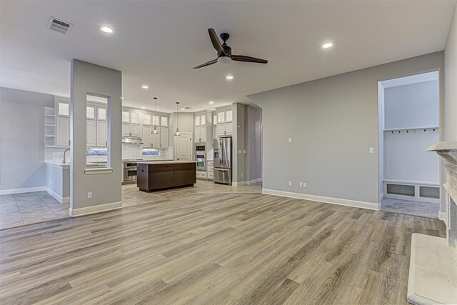 unfurnished living room featuring ceiling fan, light hardwood / wood-style flooring, and sink