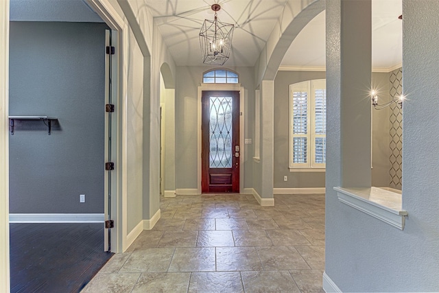 entryway with crown molding and an inviting chandelier