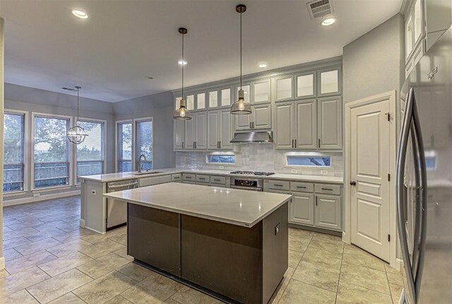 kitchen featuring appliances with stainless steel finishes, gray cabinetry, sink, a center island, and hanging light fixtures