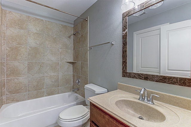 full bathroom with vanity, tiled shower / bath combo, and toilet