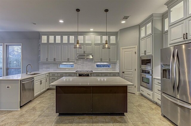 kitchen featuring pendant lighting, a center island, backsplash, sink, and stainless steel appliances