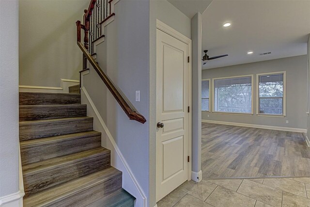 stairway with hardwood / wood-style floors and ceiling fan