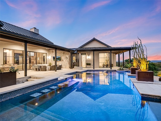 pool at dusk featuring a jacuzzi and a patio