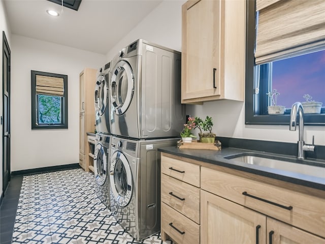 laundry area with cabinets, stacked washing maching and dryer, and sink