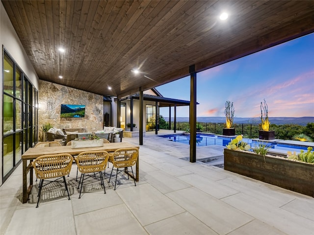 patio terrace at dusk featuring an outdoor living space and a pool with hot tub