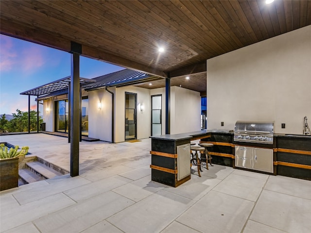 patio terrace at dusk with area for grilling and a wet bar