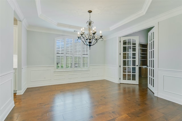 unfurnished dining area featuring french doors, dark hardwood / wood-style flooring, ornamental molding, a tray ceiling, and a chandelier