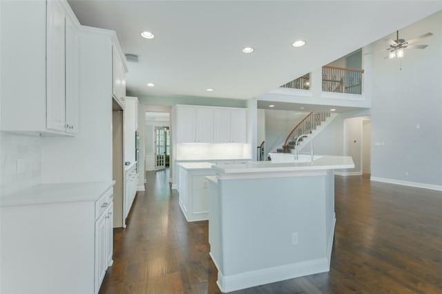 kitchen with white cabinets, dark hardwood / wood-style floors, a kitchen island, and ceiling fan