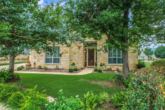 view of property hidden behind natural elements featuring stone siding