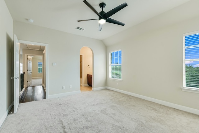 unfurnished bedroom with carpet, vaulted ceiling, ensuite bath, and ceiling fan