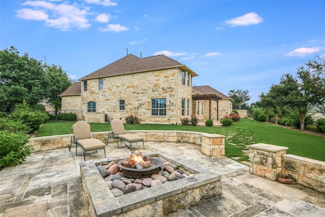 back of house featuring a patio area, a fire pit, stone siding, and a lawn