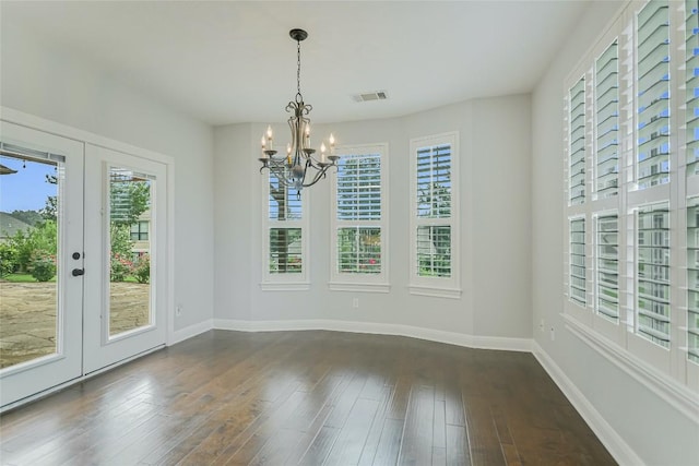 unfurnished dining area featuring a chandelier, dark wood finished floors, baseboards, and french doors