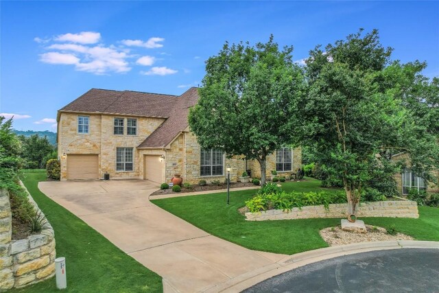 view of front of property with stone siding, concrete driveway, and a front yard