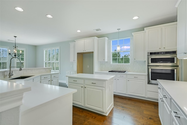 kitchen with plenty of natural light, a kitchen island, dark hardwood / wood-style flooring, and double oven