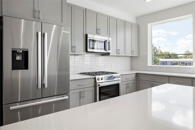 kitchen with gray cabinets, backsplash, and appliances with stainless steel finishes