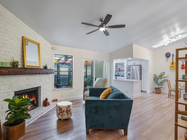 living room with ceiling fan, wood-type flooring, a fireplace, and lofted ceiling