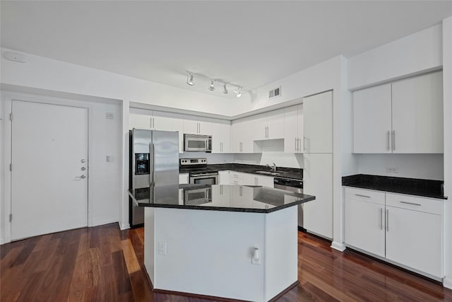 kitchen featuring appliances with stainless steel finishes, dark wood-type flooring, sink, white cabinets, and a center island